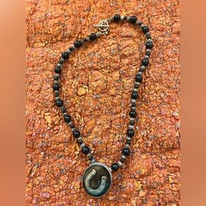 Equestrian style beaded necklace with large horseshoe pendant.